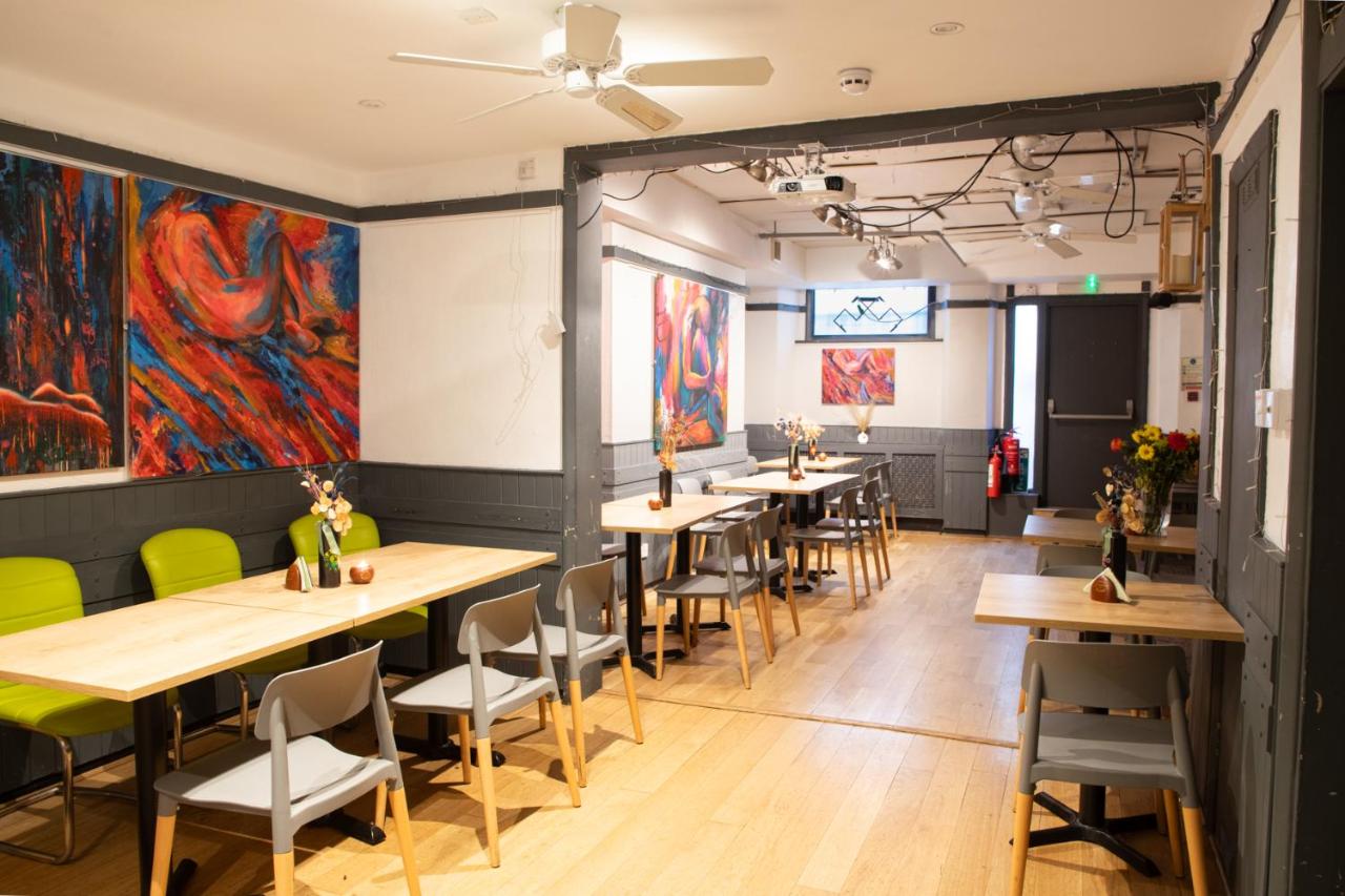 a row of tables and chairs in a restaurant with colorful paintings at 72QT in London