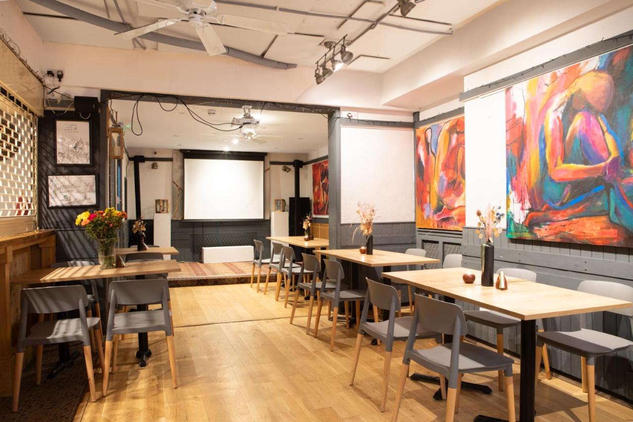 a room with tables and chairs and paintings on the walls at 72QT in London